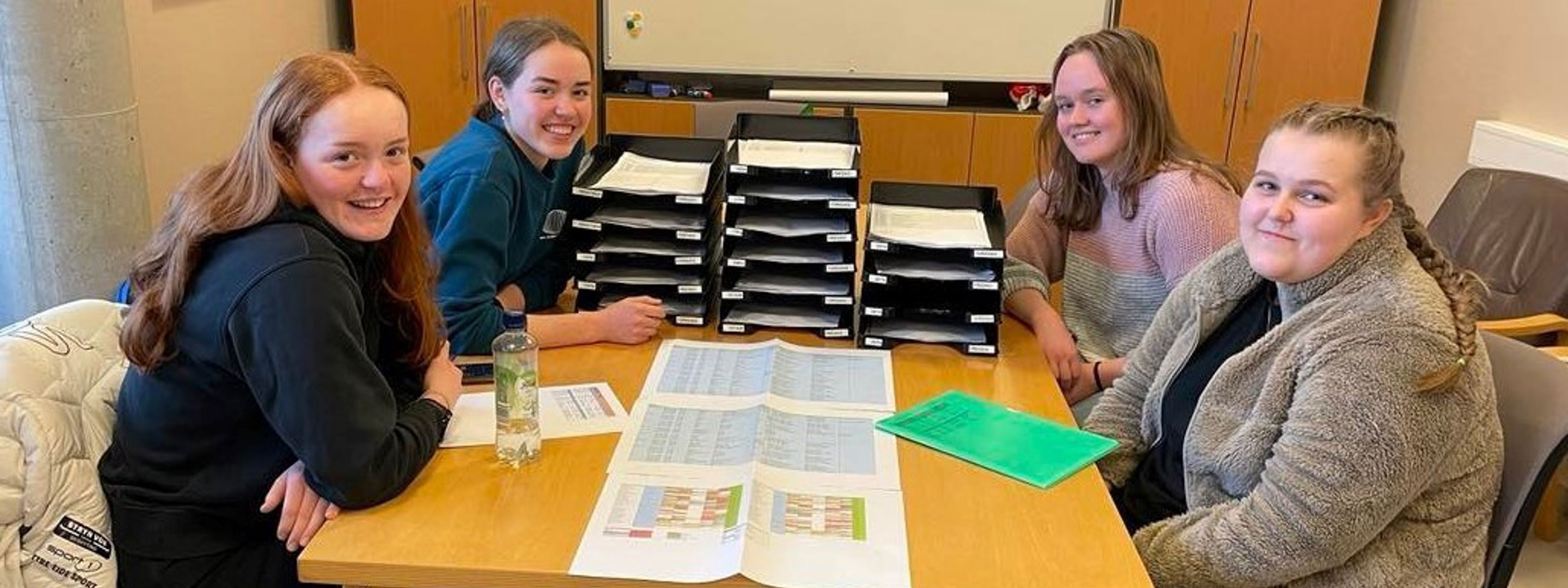 Fire jenter frå elevrådsstyret 2022/2023 som sit ved eit bord. Foto: Stryn vgs