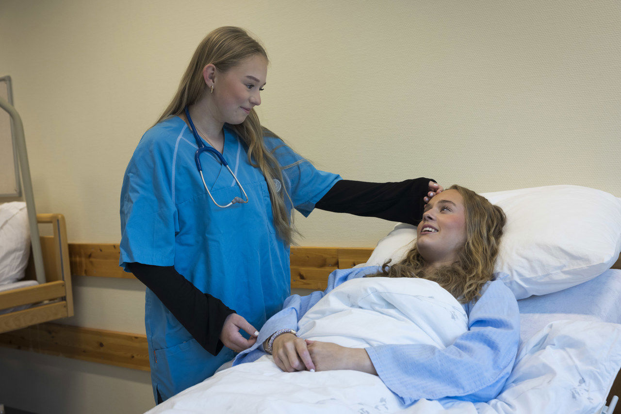 Elev på helsefag som held handa på panna til annan elev. Foto: Eurofoto