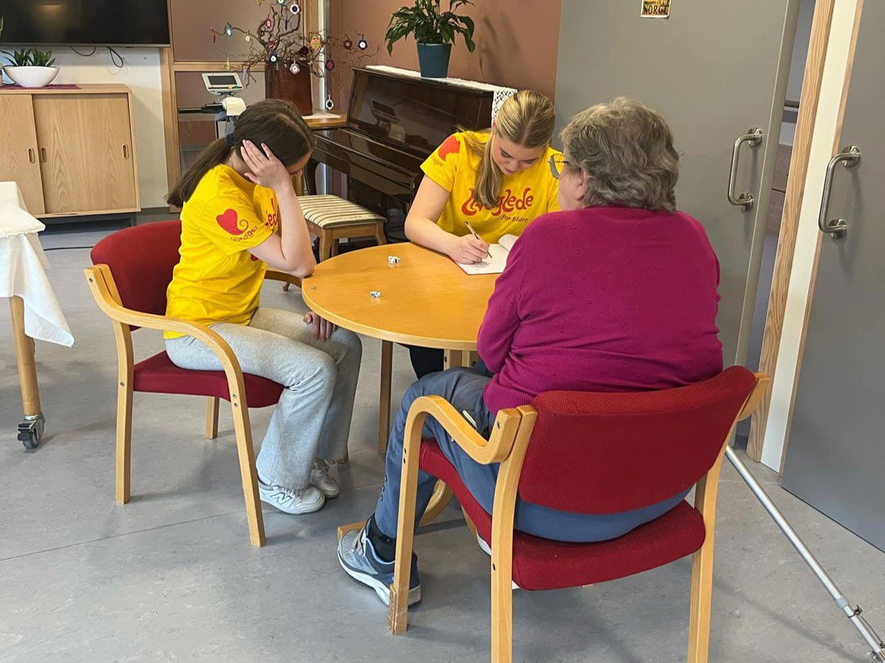To elevar spelar yatzy med bebuar på omsorgssenteret. Foto: Stryn vgs