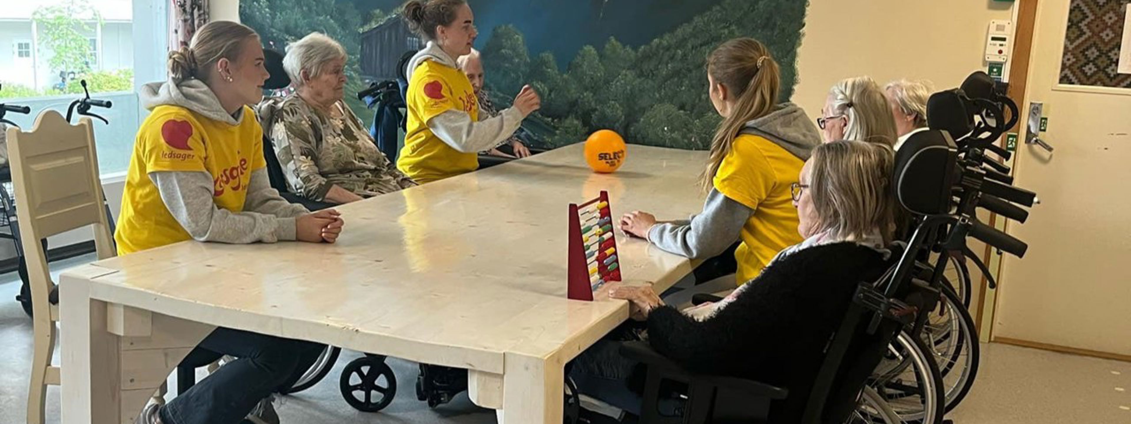 Tre elevar frå helse- og oppvekstfag samla rundt eit bord saman med bebuarar på omsorgssenteret. Foto: Stryn vgs
