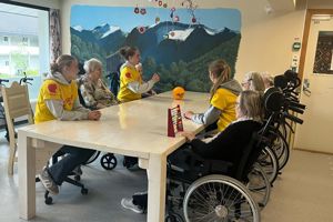 Tre elevar frå helse- og oppvekstfag samla rundt eit bord saman med bebuarar på omsorgssenteret. Foto: Stryn vgs