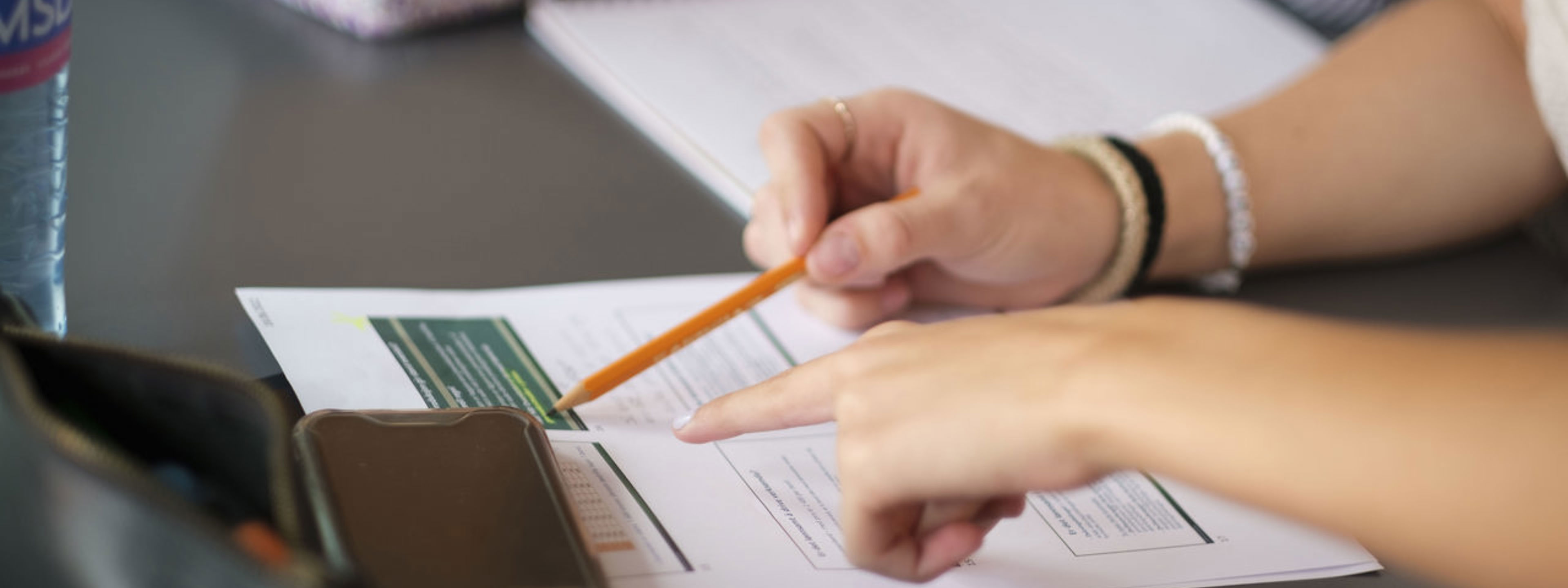 Hand som peikar på eit ark med ein blyant.